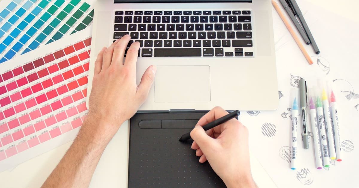 A designer working on a laptop and tablet with color swatches