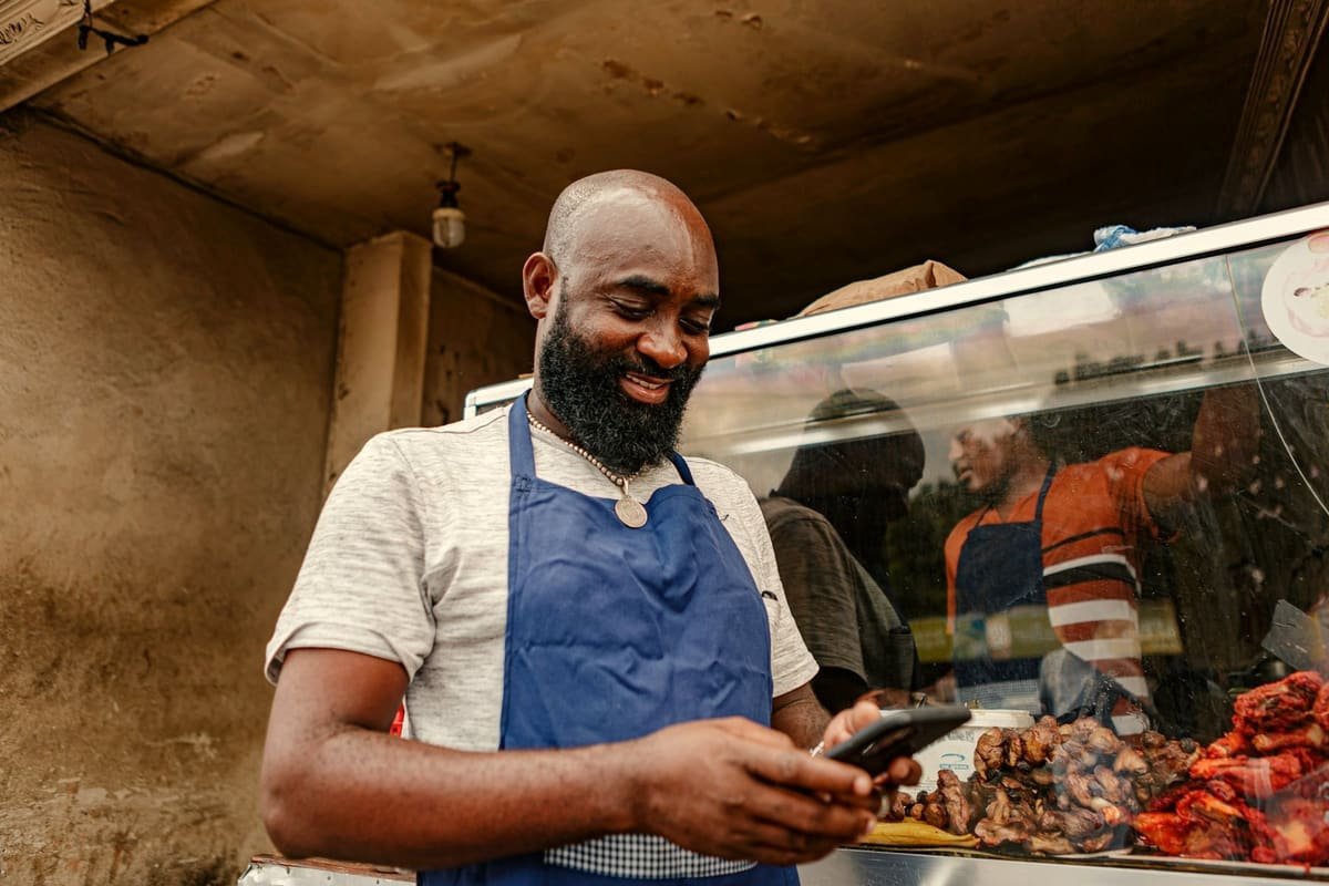 A shop owner smiling at his phone behind his counter
