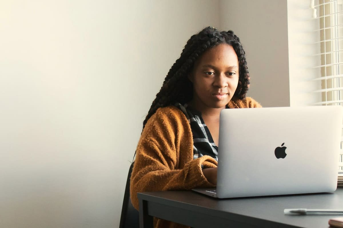 A woman working on a laptop at her desk by a window